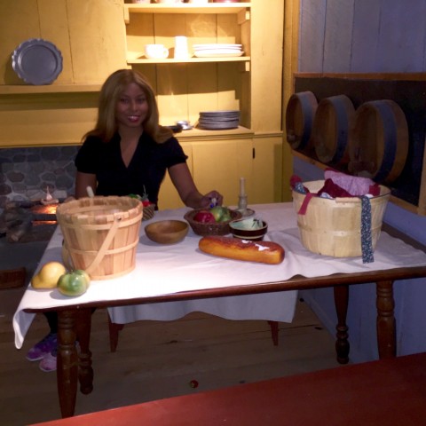 Africah sitting in the Pioneer's Kitchen. The table is set with the basic foods that was eaten during that time.